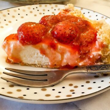 Closeup of a slice of no-bake strawberry cheesecake showing the oozy topping.