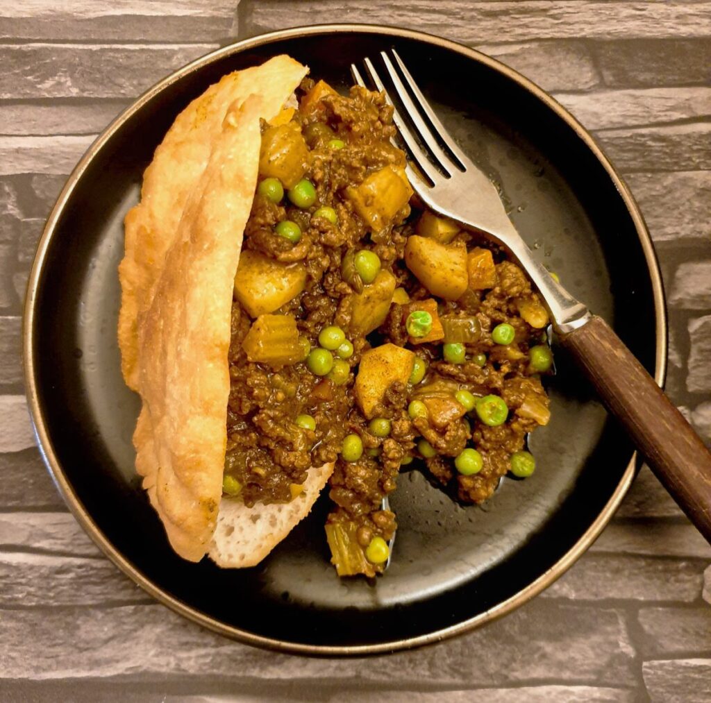 Close up of a vetkoek filled with mince curry.