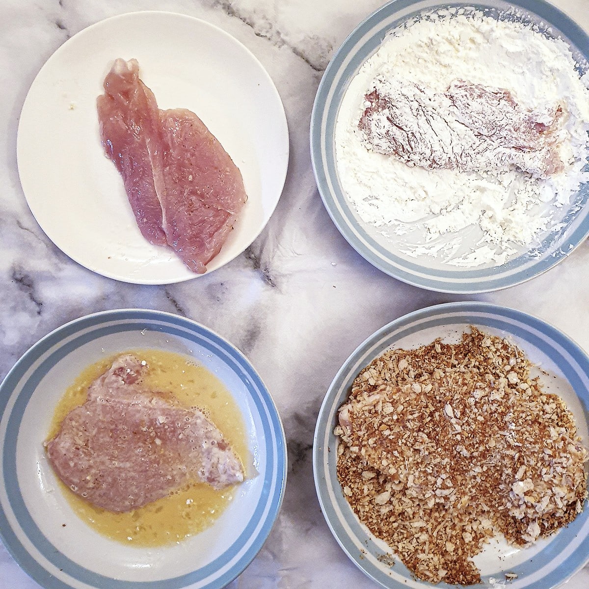 Step 1 - pieces of chicken being coated in cornflour, egg and breadcrumbs.
