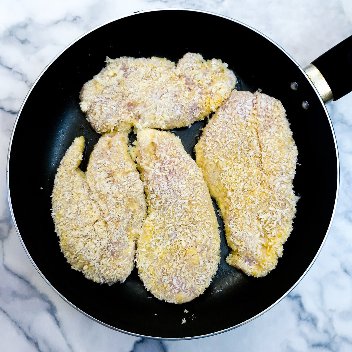 Step 6 - coated chicken being browned in a frying pan.