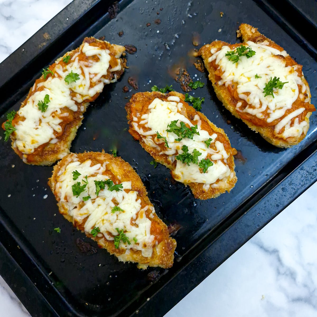 Step 9 - cooked parmesan chicken on a baking tray.