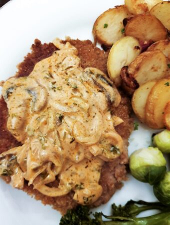 A crumbed schnitzel covered with a helping of mushroom sauce.