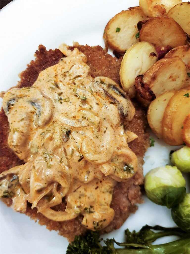 A crumbed schnitzel covered with a helping of mushroom sauce.