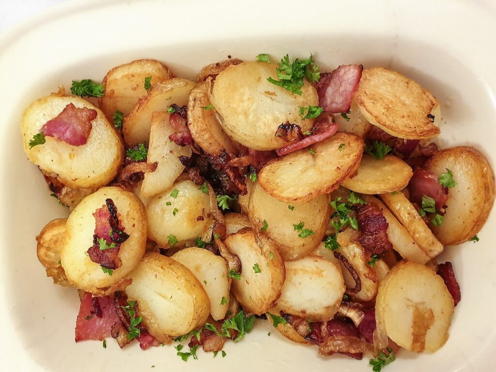 Overhead shot of a dish of German fried potatoes sprinkled with parsley.