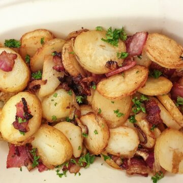 Overhead shot of a dish of German fried potatoes sprinkled with parsley.