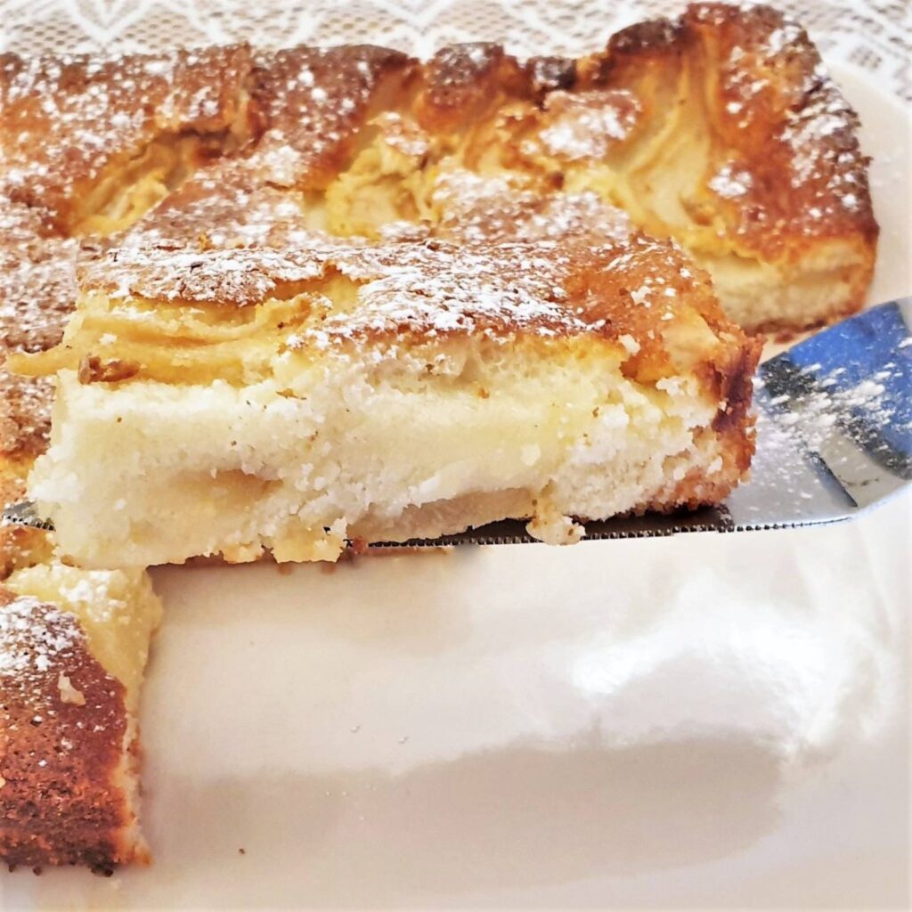 A closeup of a slice of fresh pear cream slice on a cake lifter.