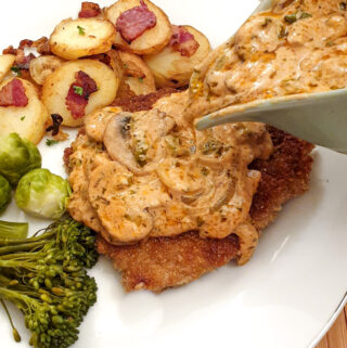 A helping of hunters sauce being poured over a schnitzel on a plate.
