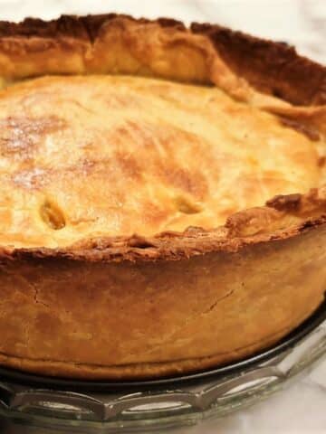 A side-on view of a baked beef and onion raised pie showing the depth of the pie.