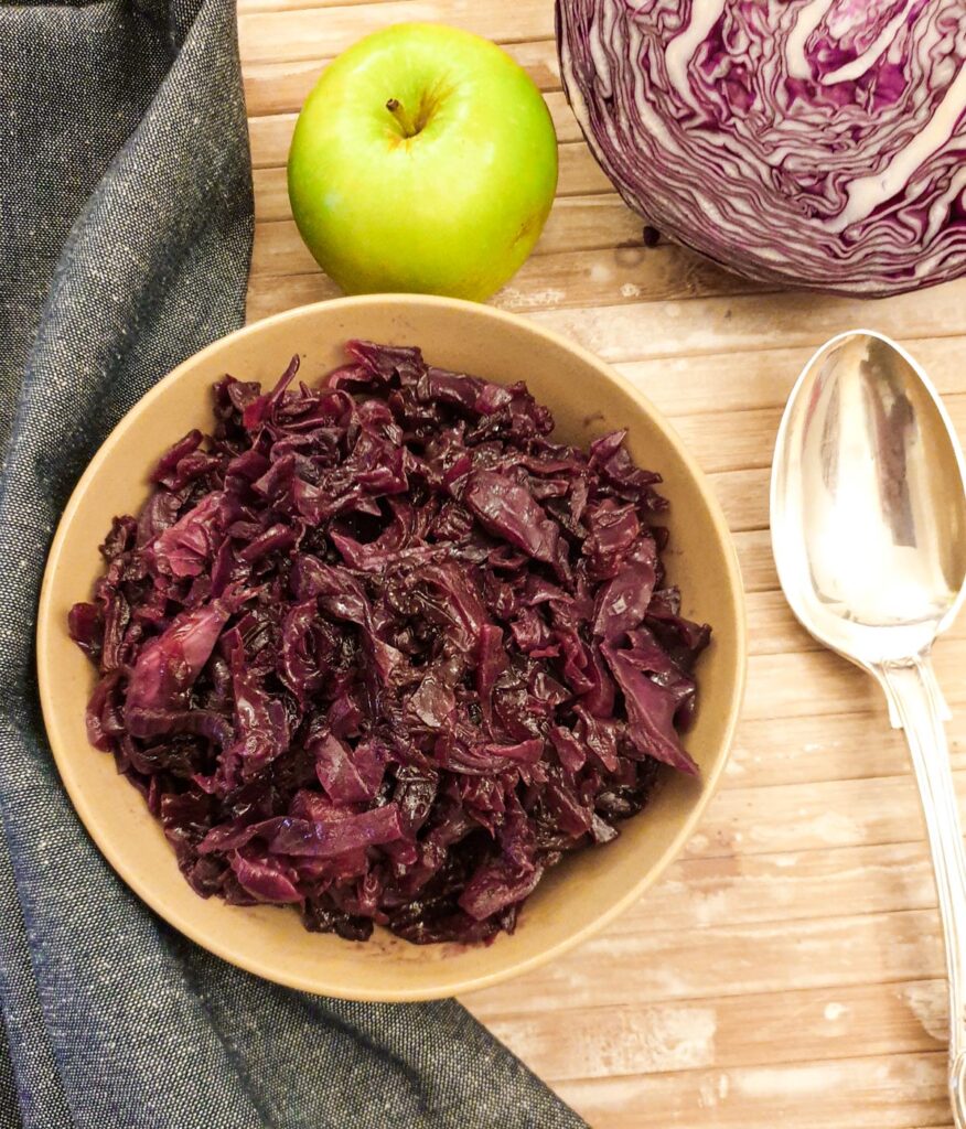 A dish of red cabbage next to a serving spoon.