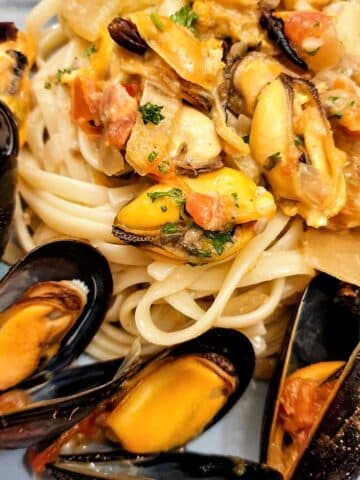 Closeup of plate of fresh mussels with pasta in a spicy tomato sauce.