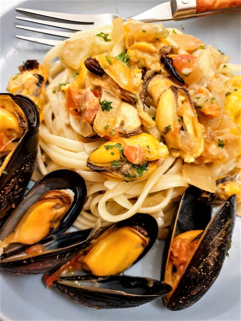 Closeup of plate of fresh mussels with pasta in a spicy tomato sauce.