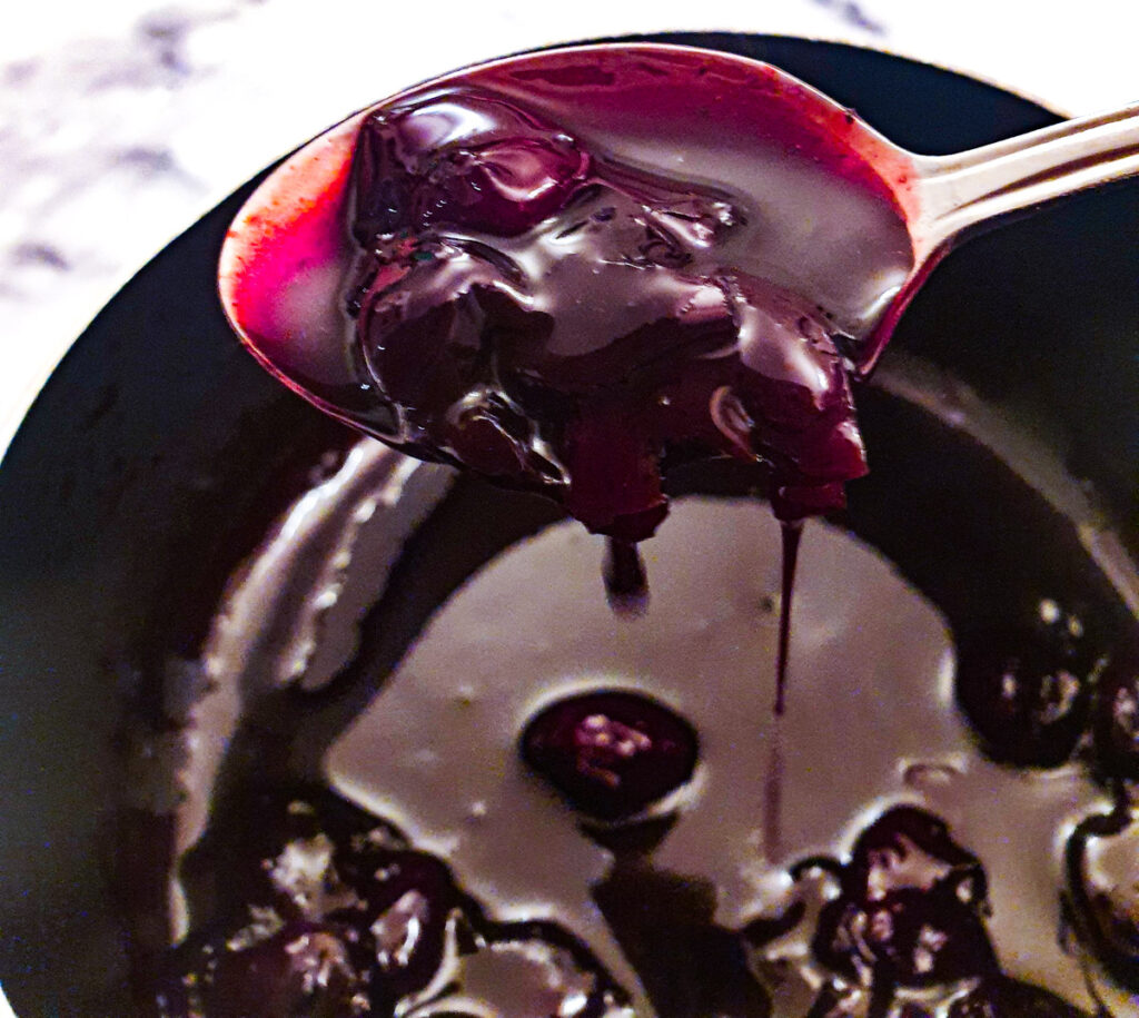 A spoonful of cherry sauce, showing the thick glossy texture.