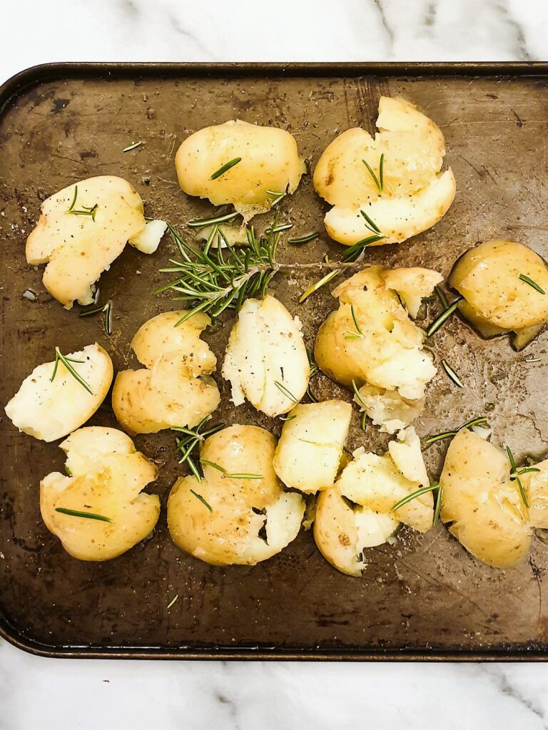 Smashed potatoes on a baking tray ready for the oven.