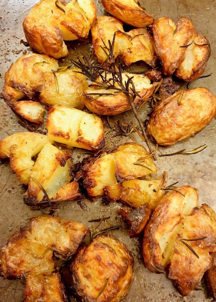 A tray of cooked rosemary smashed potatoes.