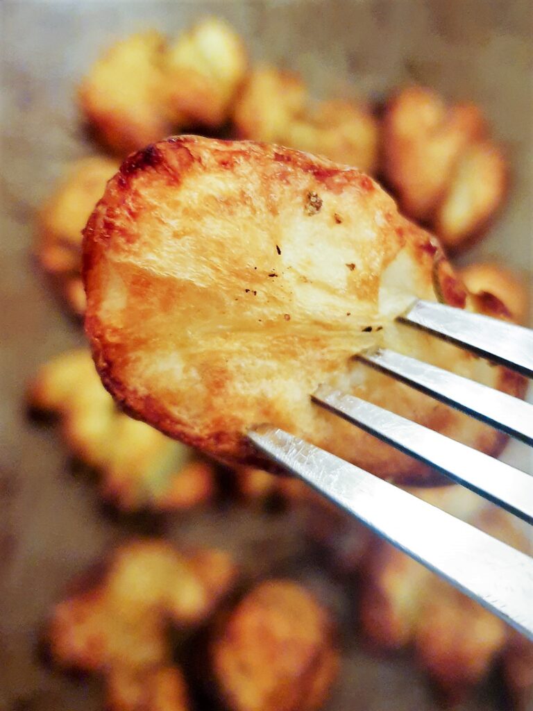 Close up of a crispy rosemary smashed potato on a fork.