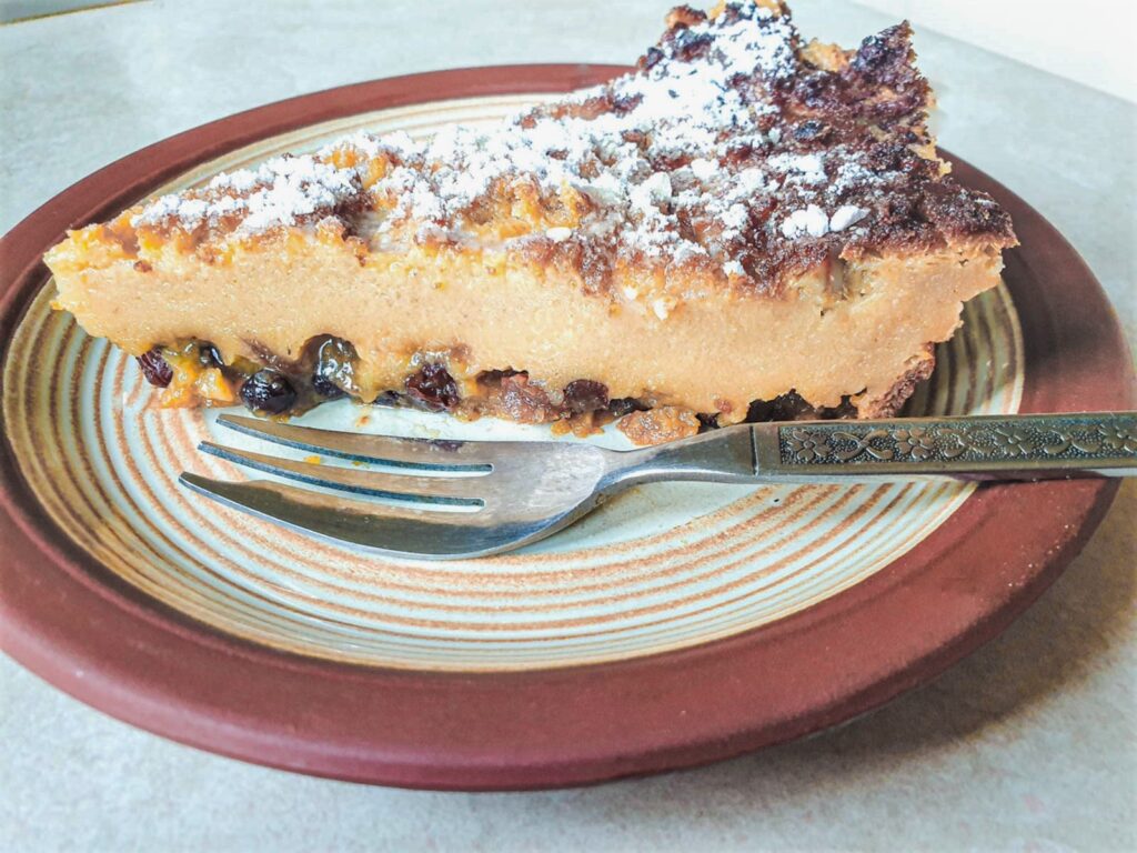 A slice of impossible Christmas pie on a plate with a dessert fork.