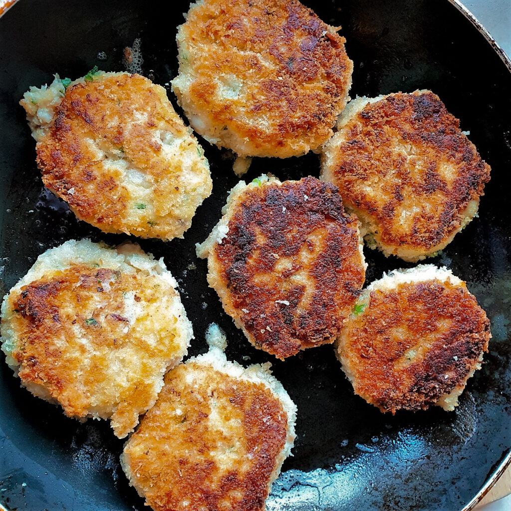 Fishcakes being browned in a frying pan