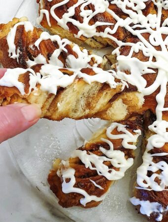 A slice of fruit mincemeat star bread covered in a tangy glaze being pulled out of the star.