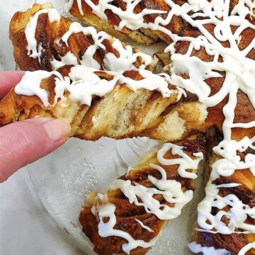 A slice of fruit mincemeat star bread covered in a tangy glaze being pulled out of the star.