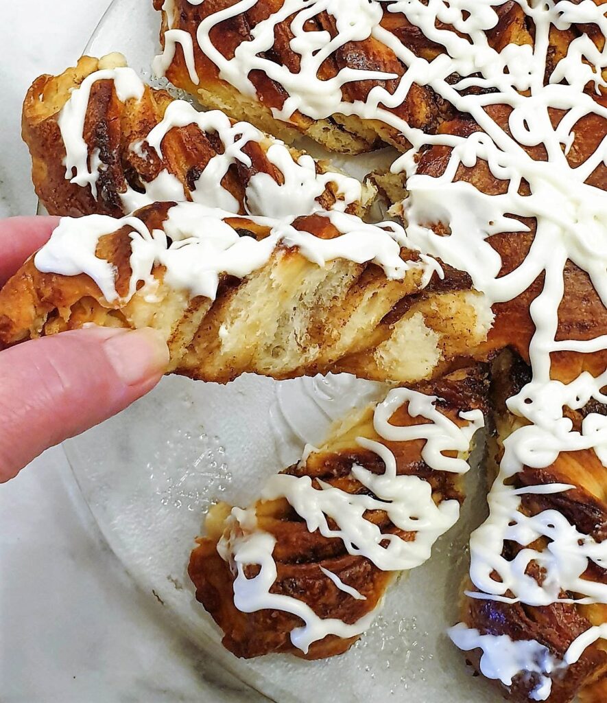 A slice of fruit mincemeat star bread covered in a tangy glaze being pulled out of the star.