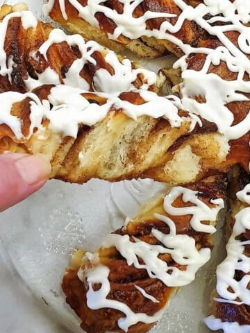 A slice of fruit mincemeat star bread covered in a tangy glaze being pulled out of the star.