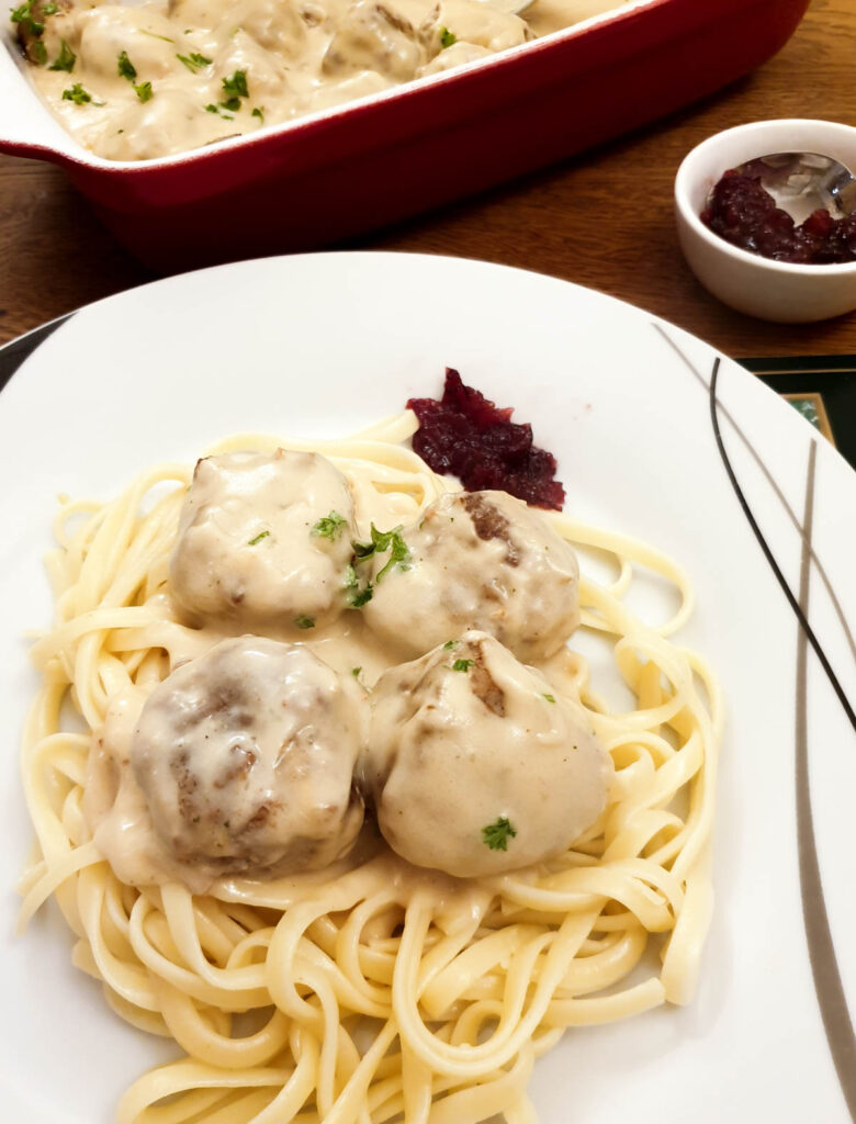 4 meatballs on a plate on a bed of spaghetti.