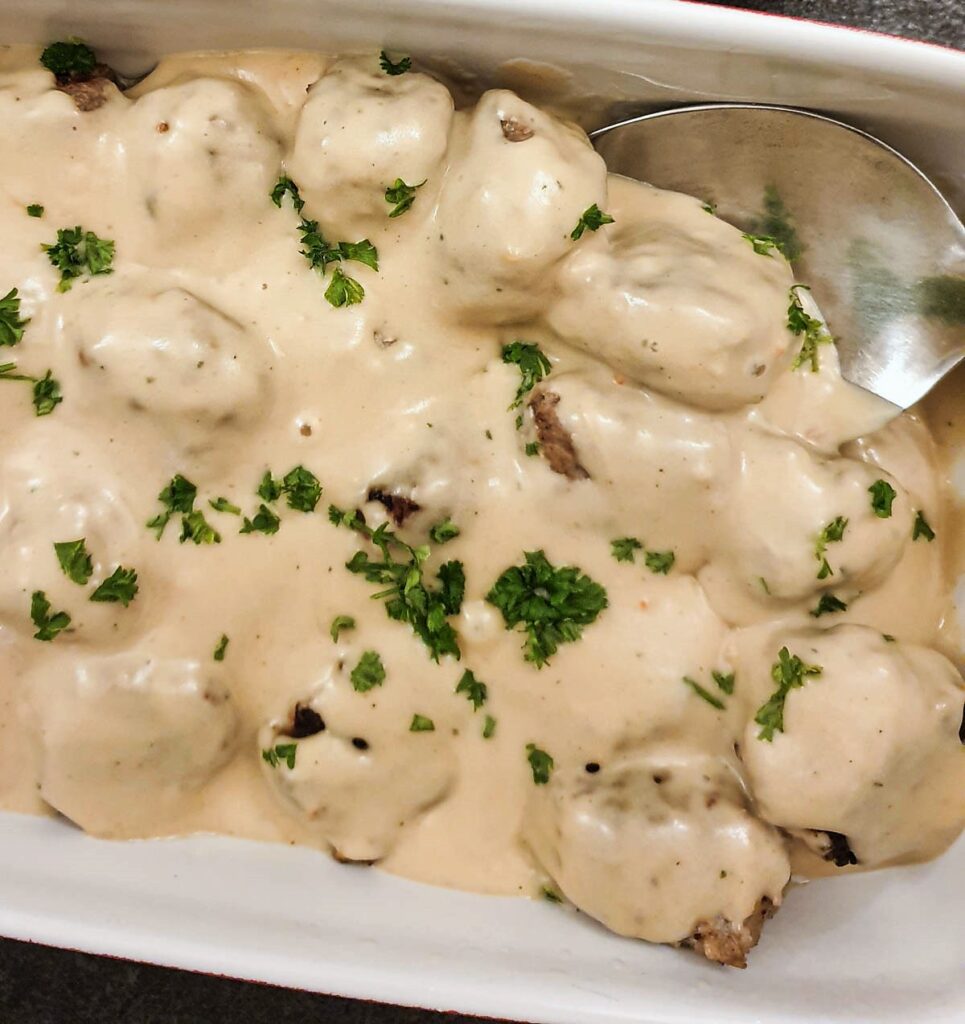 A dishful of meatballs covered with mustard sauce.