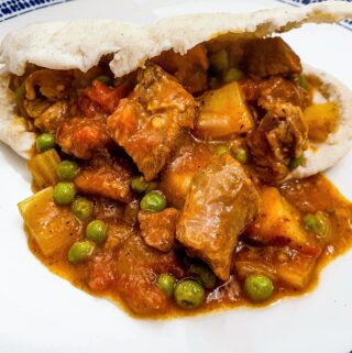 A plate of lamb curry in a pita bread.