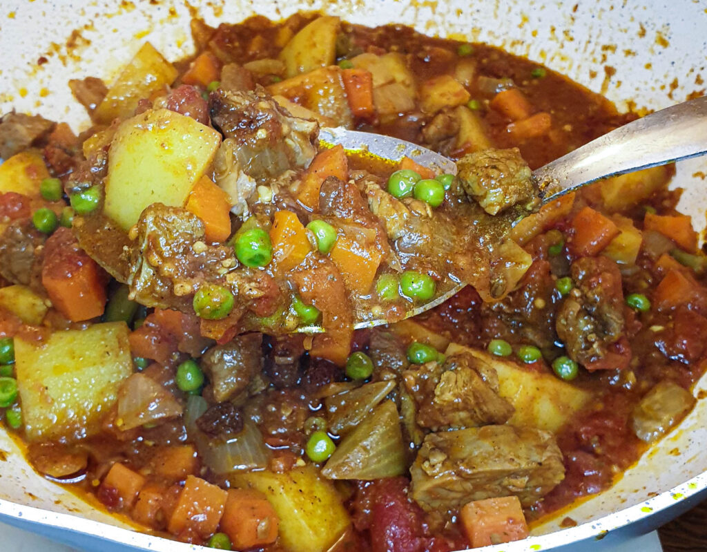 A spoonful of lamb curry over the serving dish.