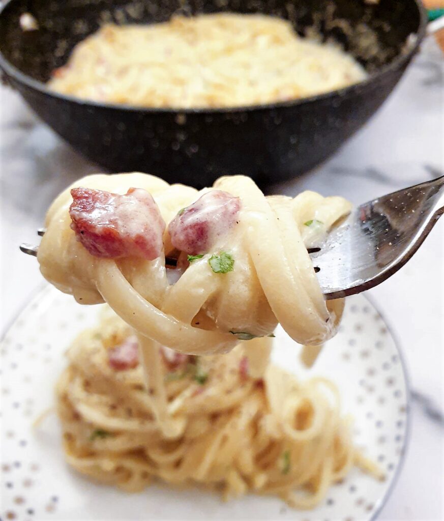 A close up of spaghetti carbonara wrapped around a fork.