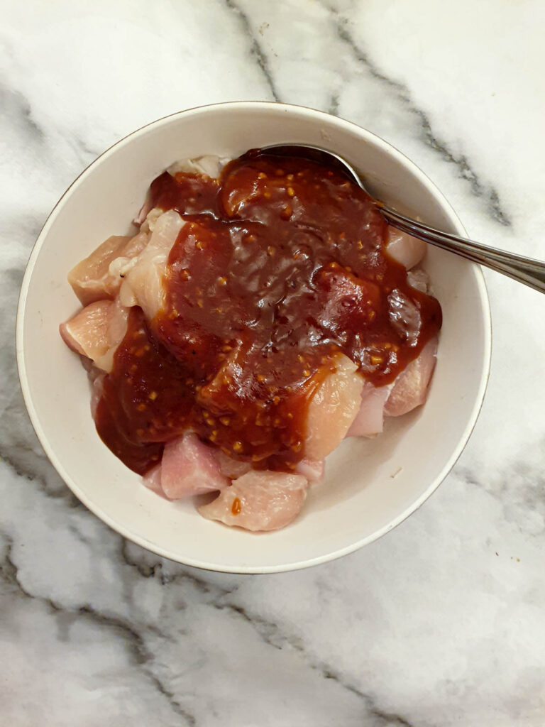 A dish of chicken cubes covered with marinade.