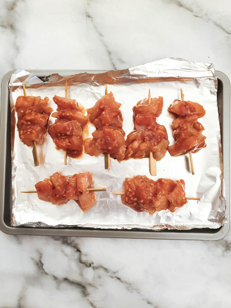 Chicken skewers on a baking tray ready for the oven.