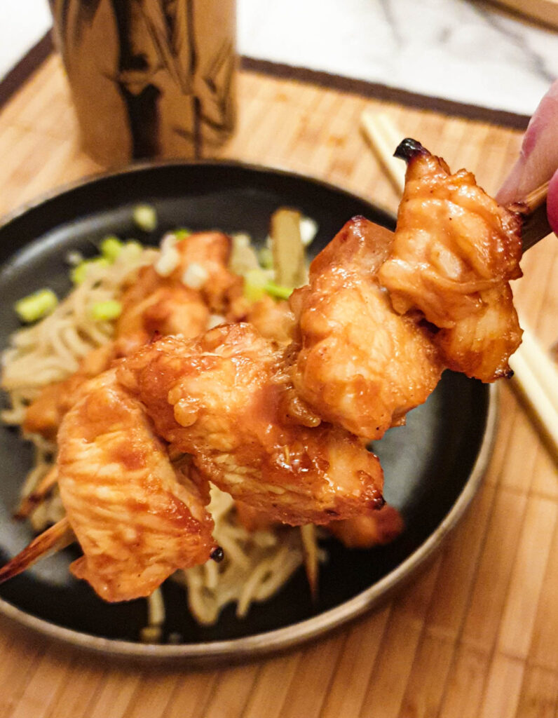 Close up of a sticky chicken skewer.