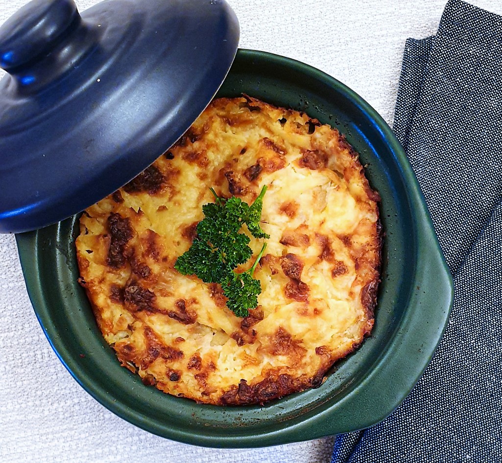 A small ramekin of potatoes Romanoff seen from above.