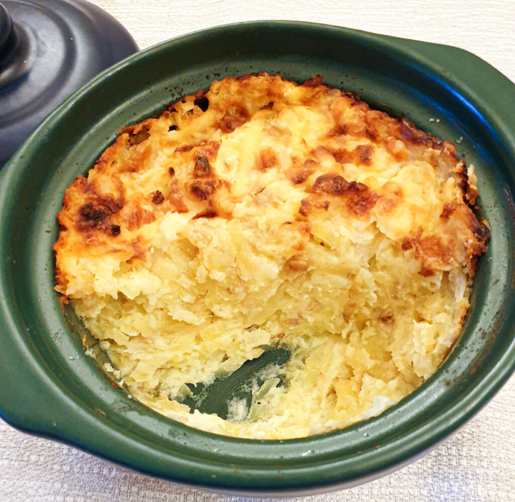 Potatoes Romanoff in a dish with a spoonful removed to show the texture.