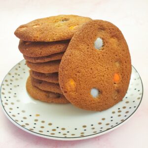 A pile of giant Smartie cookies on a plate with one cookie standing on its side.