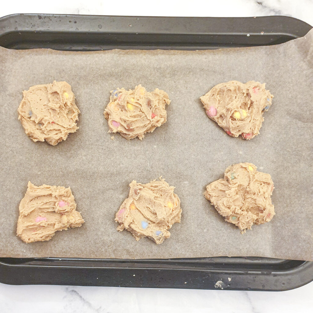 6 spoonfuls of cookie dough on a baking sheet.