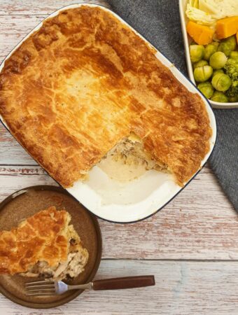 An overhead shot of granny's chicken pie with a slice removed and served on a plate next to the baking dish.