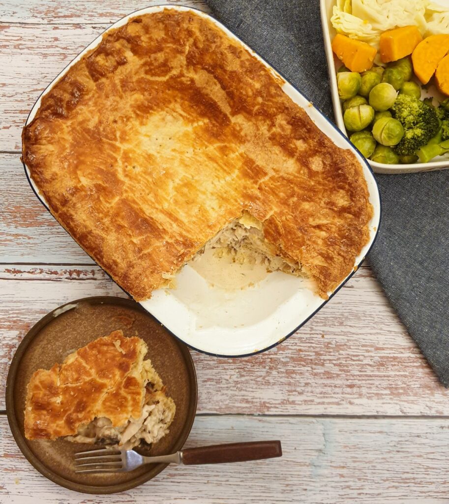 An overhead shot of granny's chicken pie with a slice removed and served on a plate next to the baking dish.