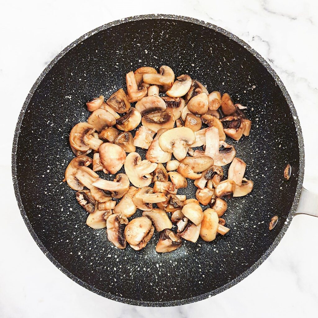 Mushrooms frying in a pan.