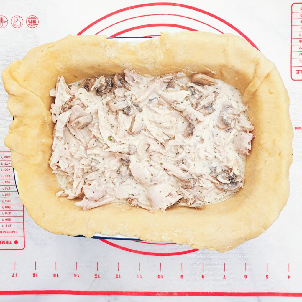  A baking dish lined with pastry and filled with chicken and mushroom filling.