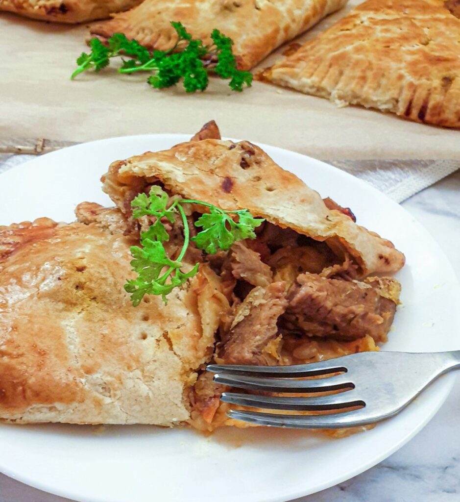 A lamb pie on a plate, cut open to show the meat inside.