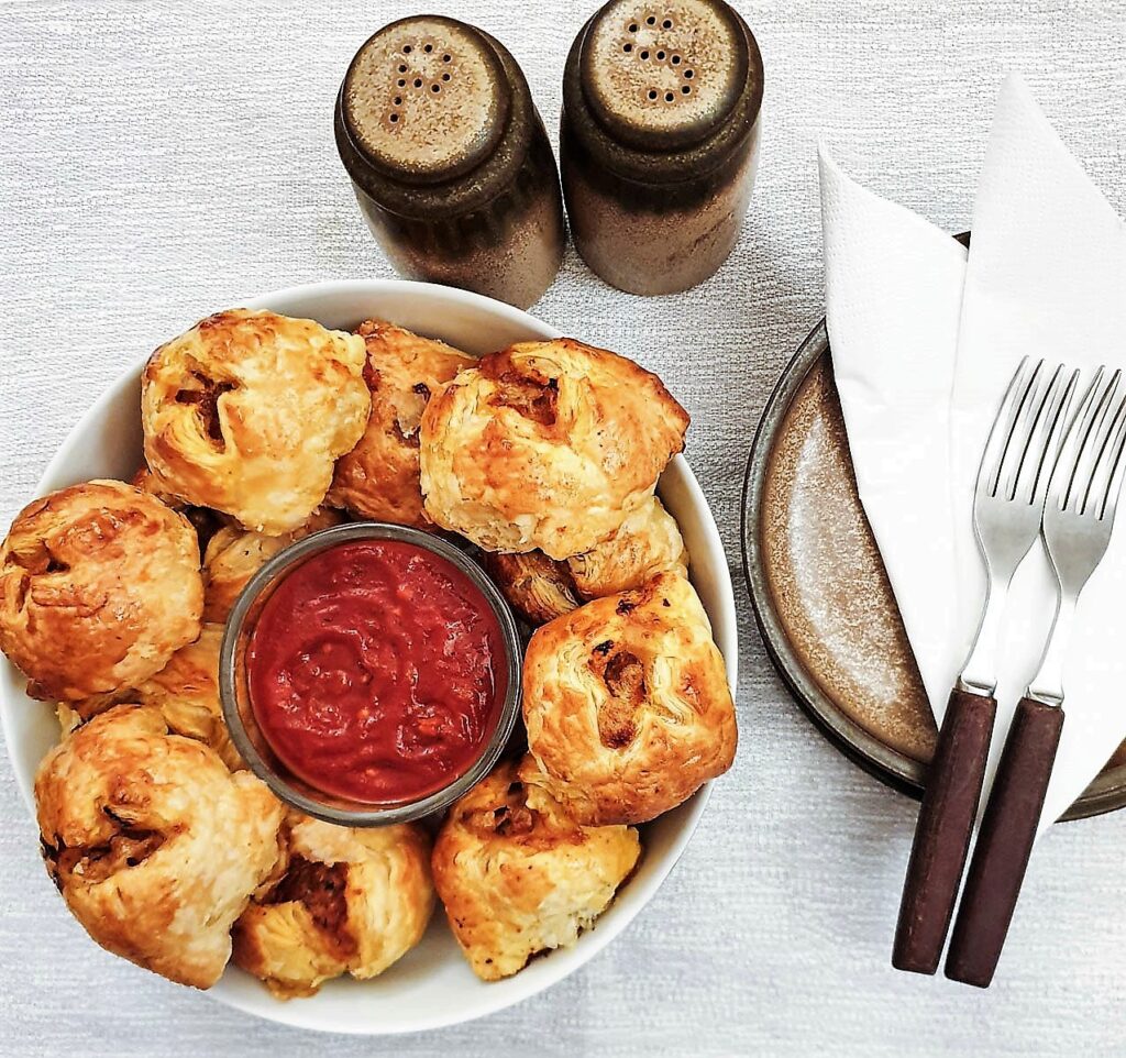 A plate of meatball wellingtons surrounding a dish of marinara sauce.