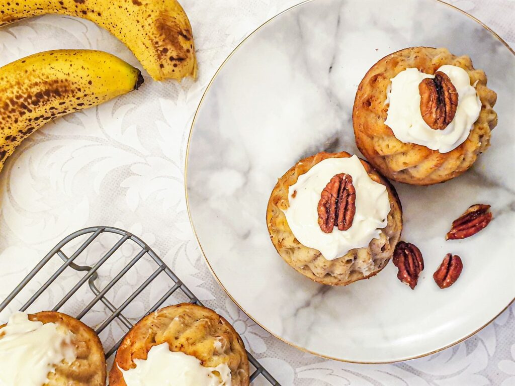 Two bundt cakes on a plate next to two bananas.