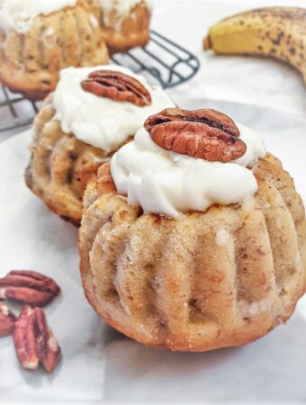 Close up of a pecan and banana bundt cake filled with lemon cheese frosting and topped with a pecan nut.