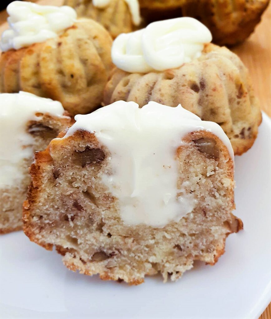A pecan and banana bundt cake cut in half to show the hole in the middle filled with frosting.