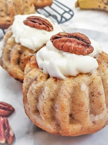 Close up of a pecan and banana bundt cake filled with lemon cheese frosting and topped with a pecan nut.