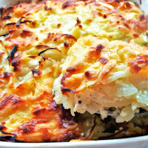 A spoonful of potato and onion bake being lifted from the dish.