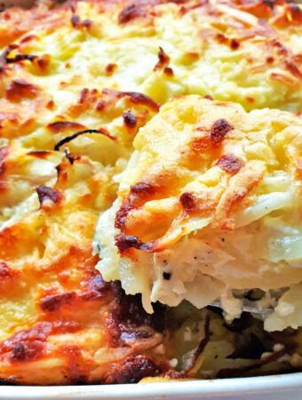 A spoonful of potato and onion bake being lifted from the dish.