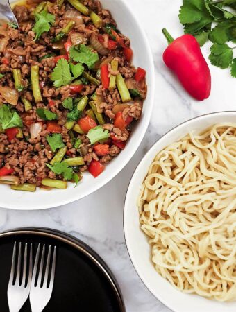 Overhead shot of a dish of Thai pork mince stir fry with a dish of noodles.